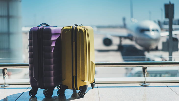 Suitcases in an airport, with a plane visible in the background